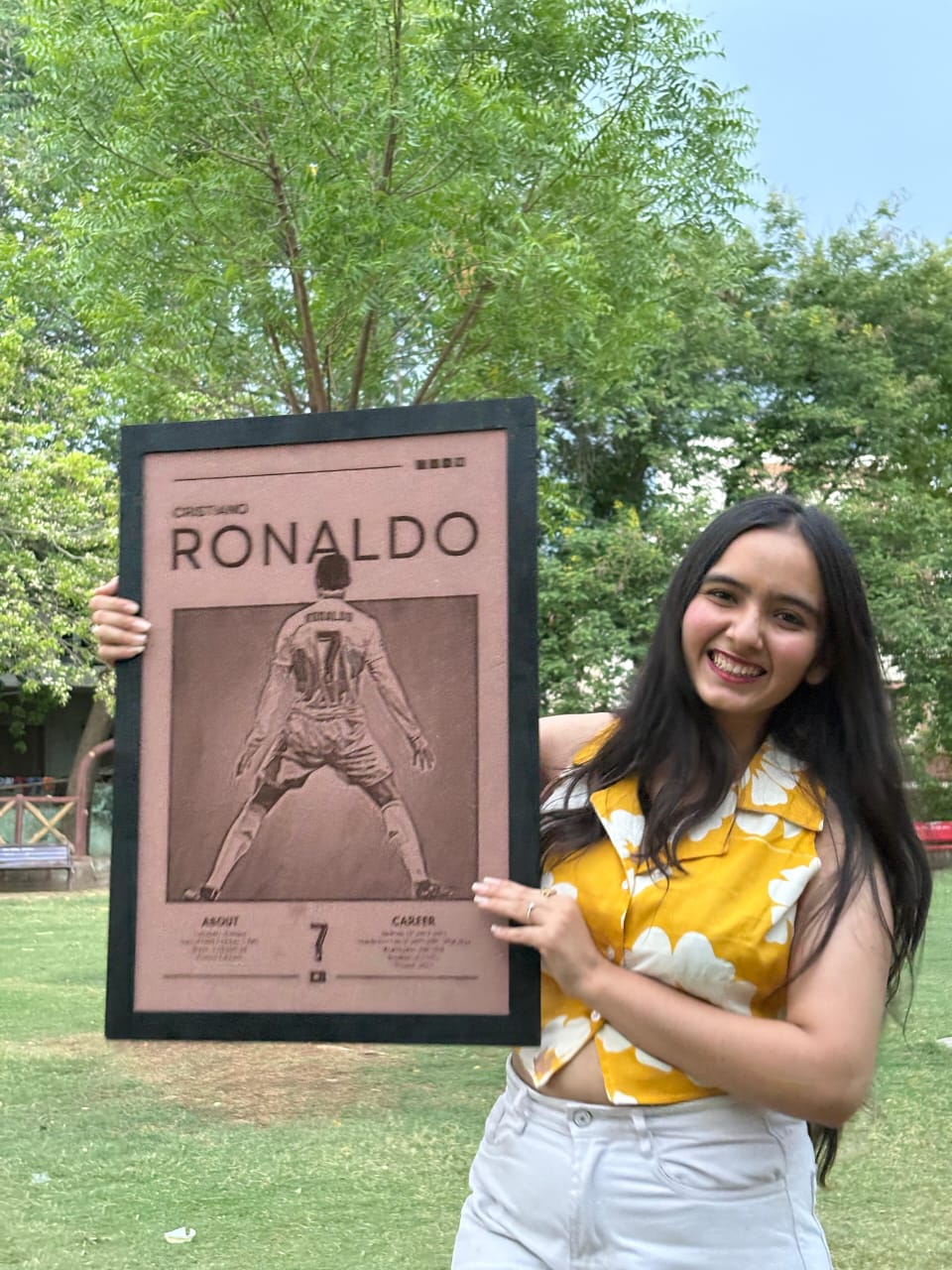 Woman holding a framed picture of a soccer player outdoors