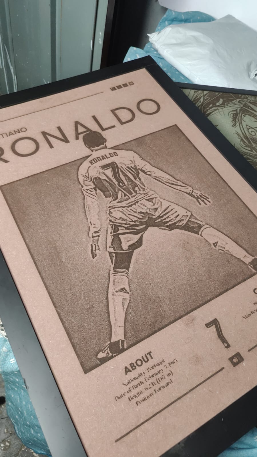 Framed poster of a soccer player with 'Ronaldo' on it, displayed on a surface.